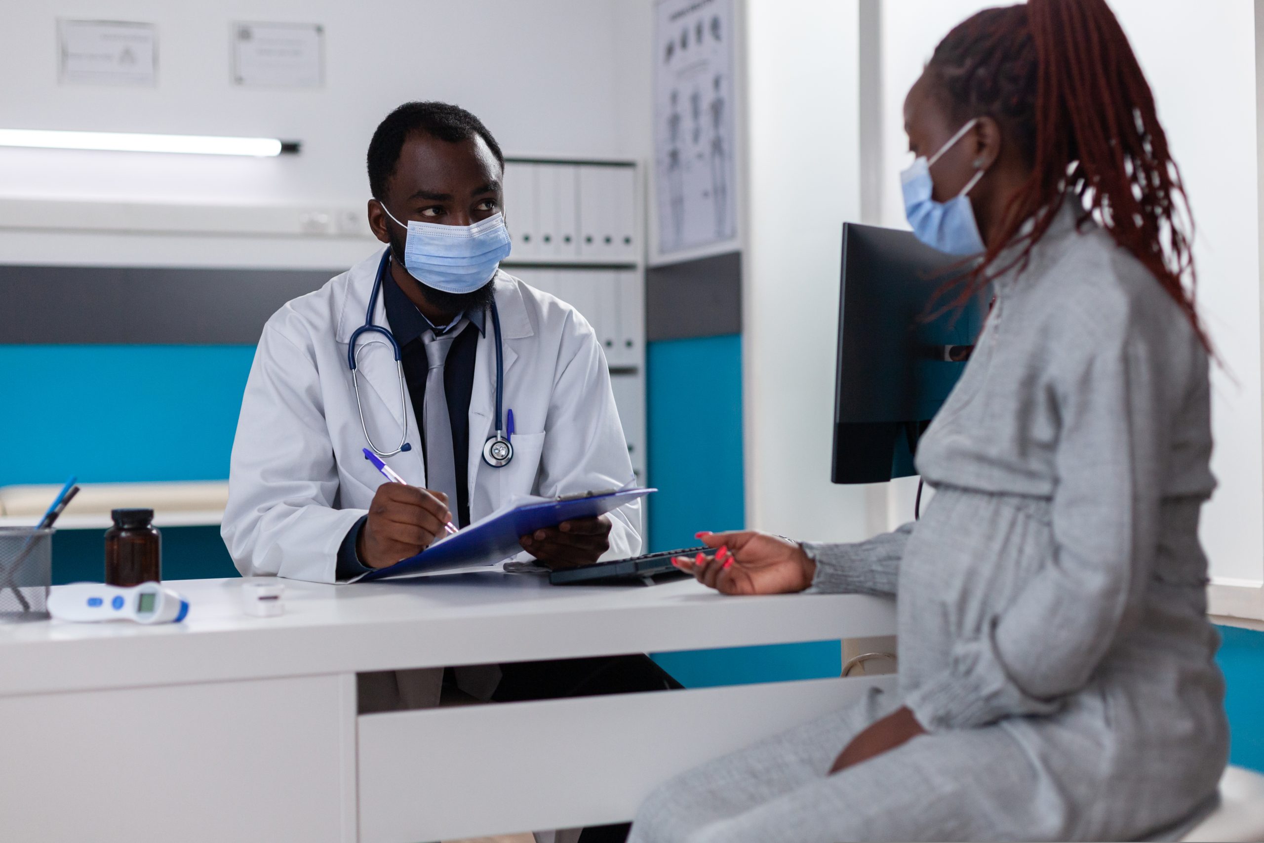 African american medic and pregnant woman talking about healthcare and support. Physician giving medical advice to young patient expecting child during coronavirus pandemic